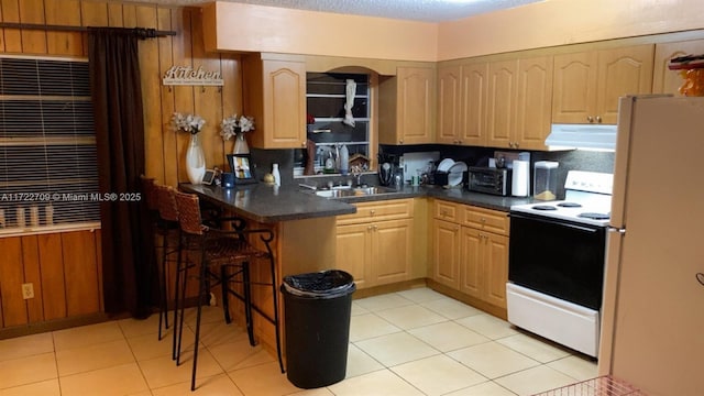 kitchen featuring white appliances, dark countertops, range hood, and a sink