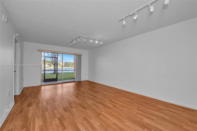 spare room with a textured ceiling and light hardwood / wood-style flooring