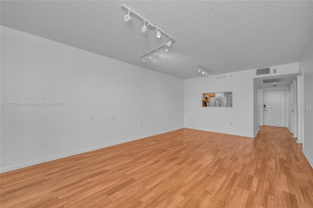 unfurnished room featuring light wood-type flooring and a textured ceiling