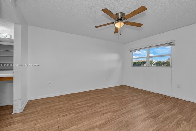 empty room featuring ceiling fan, a textured ceiling, and light hardwood / wood-style flooring