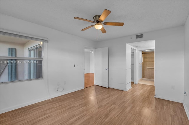 unfurnished bedroom with ceiling fan, a textured ceiling, ensuite bathroom, and light wood-type flooring