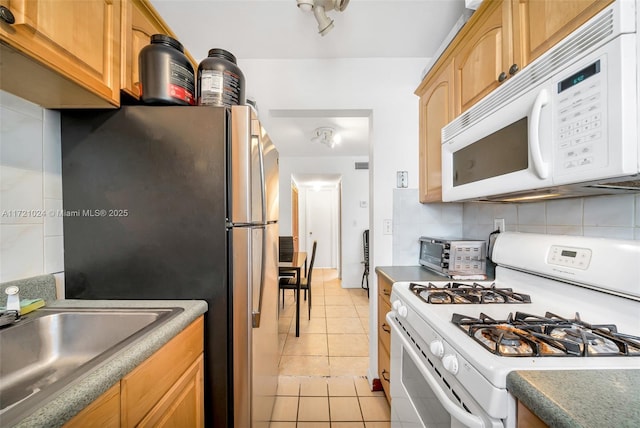 kitchen with white appliances, sink, light tile patterned floors, and tasteful backsplash