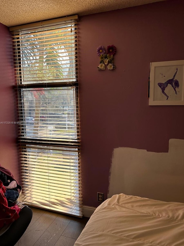 bedroom featuring multiple windows, hardwood / wood-style floors, and a textured ceiling