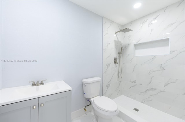 bathroom with a tile shower, vanity, and toilet