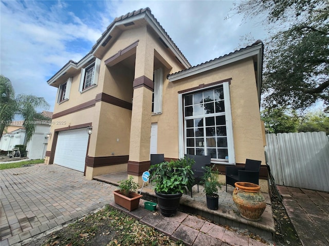 5323 NW 109th Ct, Doral, FL 33178 - view of side of property with stucco siding, fence, decorative driveway, a garage, and a tile roof