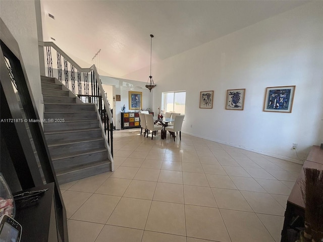 dining area featuring stairs, high vaulted ceiling, light tile patterned floors, and baseboards