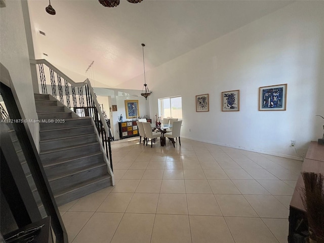 interior space featuring stairs, high vaulted ceiling, tile patterned flooring, and baseboards