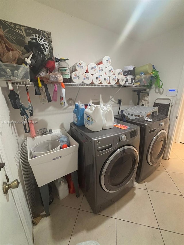 clothes washing area featuring laundry area, tile patterned flooring, and washer and clothes dryer