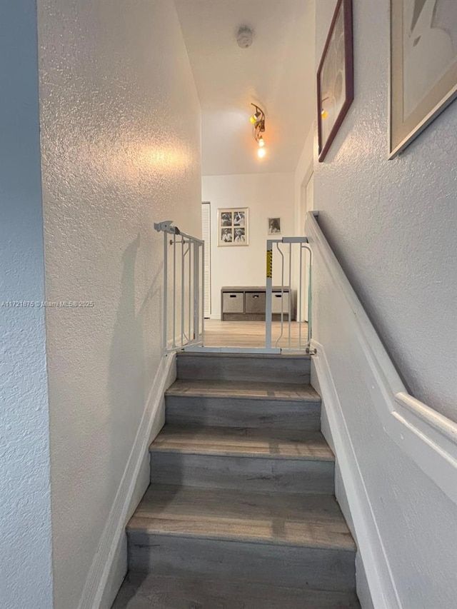 stairway with a textured wall and wood finished floors