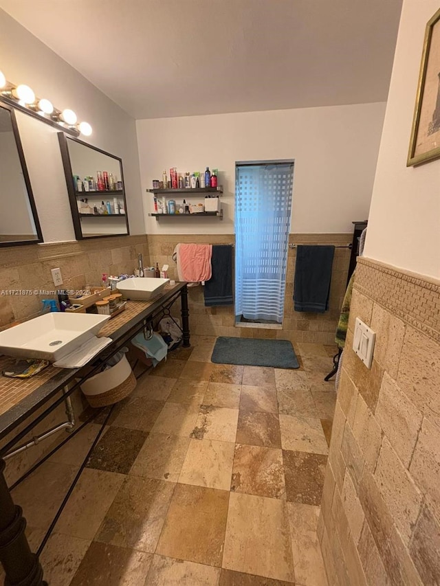 bathroom featuring wainscoting, a sink, and tile walls