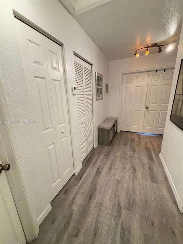 hall featuring dark wood-style flooring, a textured ceiling, and baseboards