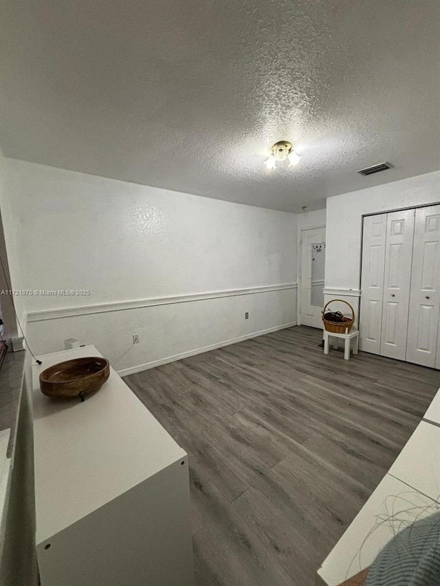 interior space with a textured ceiling, visible vents, and dark wood-type flooring