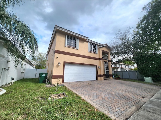 view of front facade with an attached garage, fence, decorative driveway, stucco siding, and a front yard