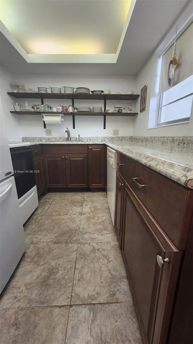 kitchen featuring light stone countertops, dark brown cabinetry, and white dishwasher