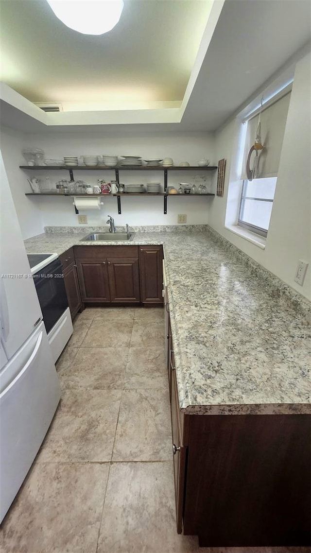 kitchen featuring dark brown cabinets, white appliances, sink, and kitchen peninsula