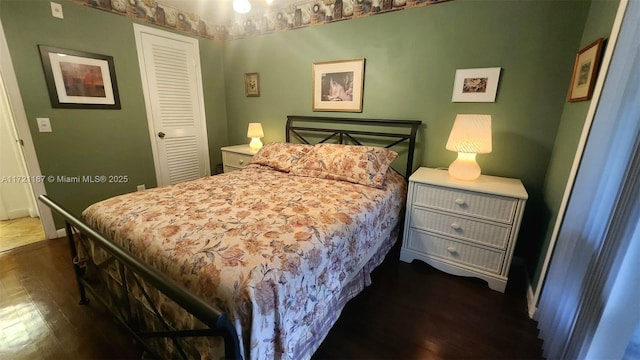 bedroom with dark hardwood / wood-style flooring and a closet