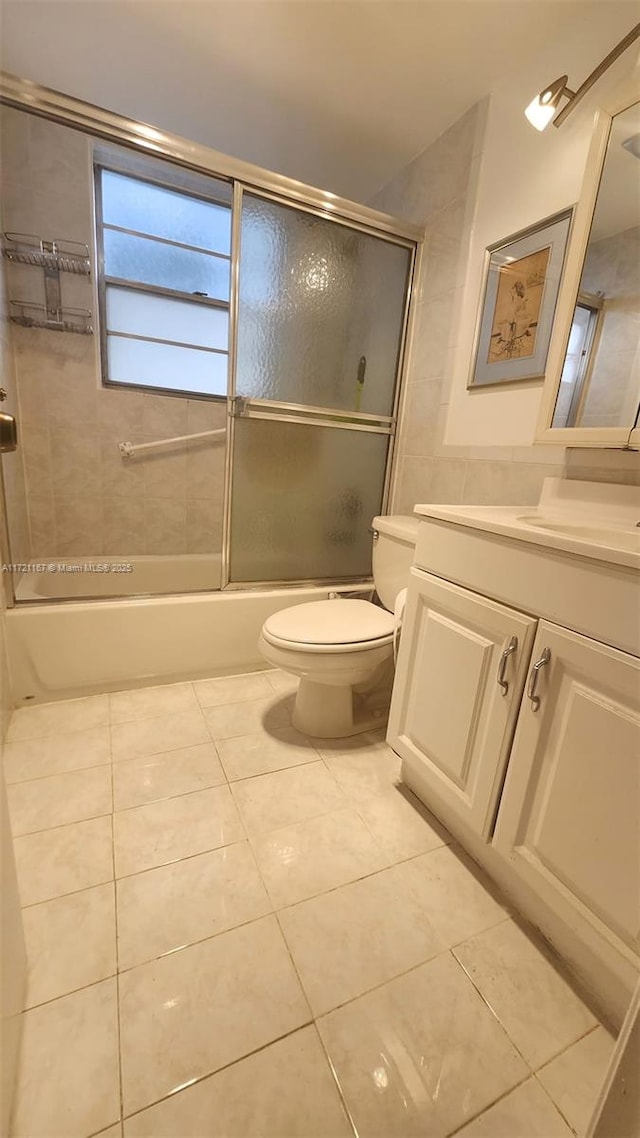 full bathroom featuring shower / bath combination with glass door, vanity, tile patterned floors, and toilet