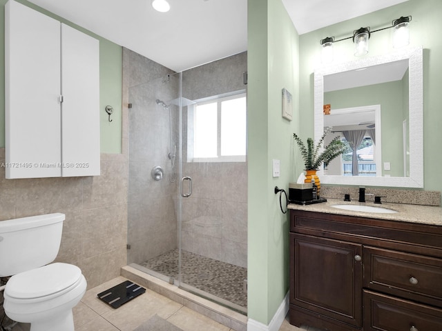 bathroom featuring tile patterned flooring, tile walls, vanity, toilet, and walk in shower