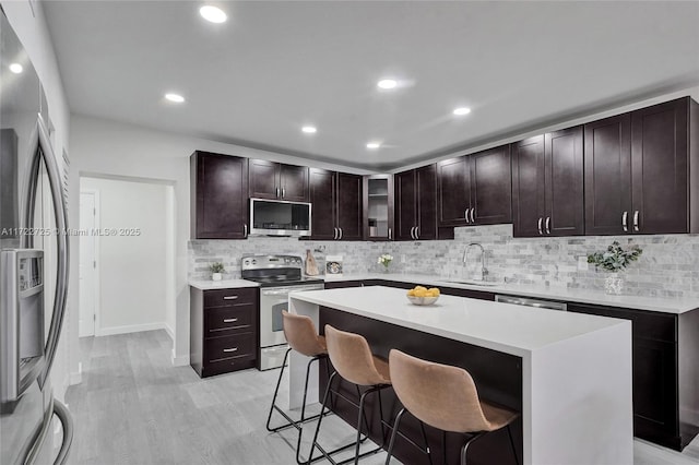 kitchen featuring a breakfast bar, dark brown cabinets, stainless steel appliances, sink, and a center island