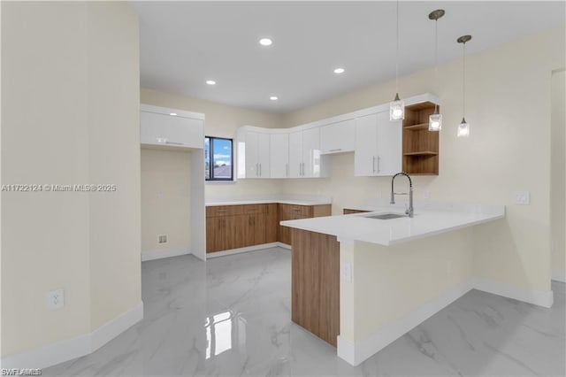 kitchen featuring white cabinets, kitchen peninsula, hanging light fixtures, and sink