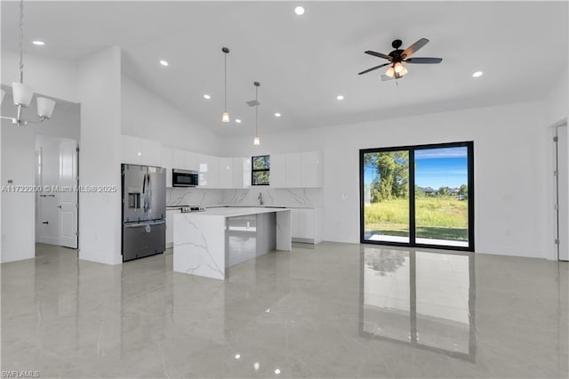 kitchen featuring ceiling fan with notable chandelier, hanging light fixtures, a kitchen island, white cabinetry, and stainless steel appliances