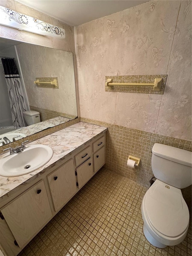 bathroom featuring toilet, vanity, tile walls, and tile patterned floors