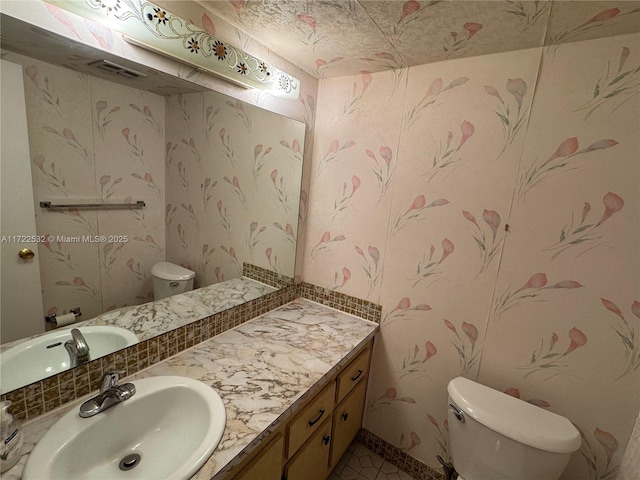 bathroom featuring toilet, vanity, and tile patterned flooring