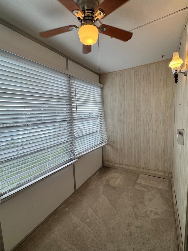 carpeted spare room with ceiling fan and wooden walls