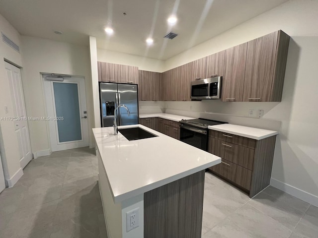 kitchen with sink, a kitchen island with sink, and appliances with stainless steel finishes