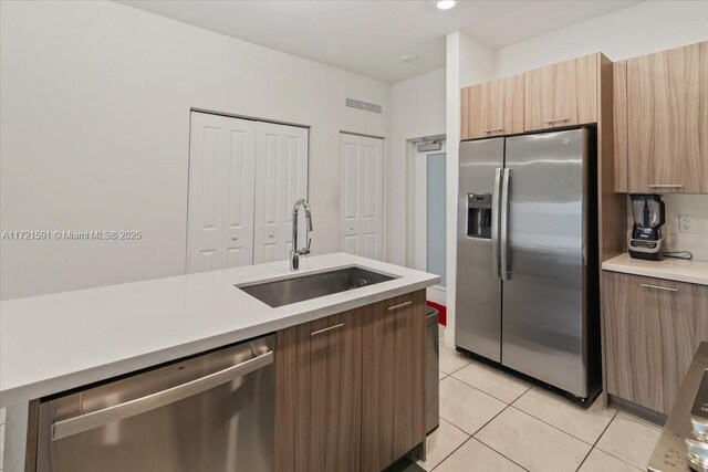 kitchen with sink, stainless steel appliances, and light tile patterned flooring