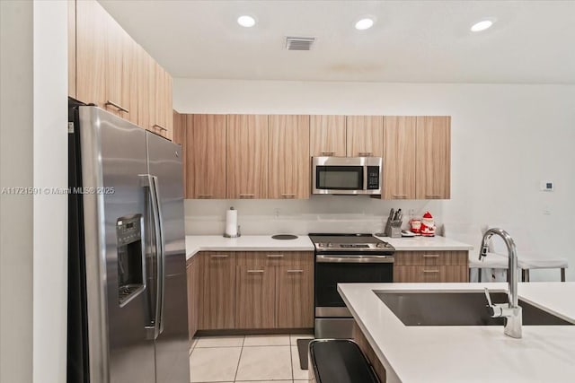 kitchen with appliances with stainless steel finishes, sink, and light tile patterned floors