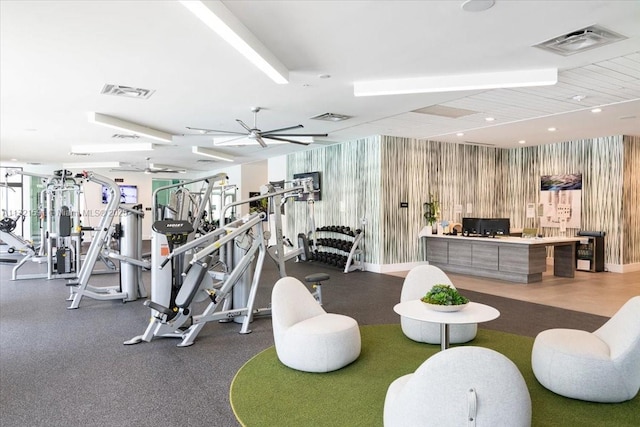 exercise room with ceiling fan and wood walls