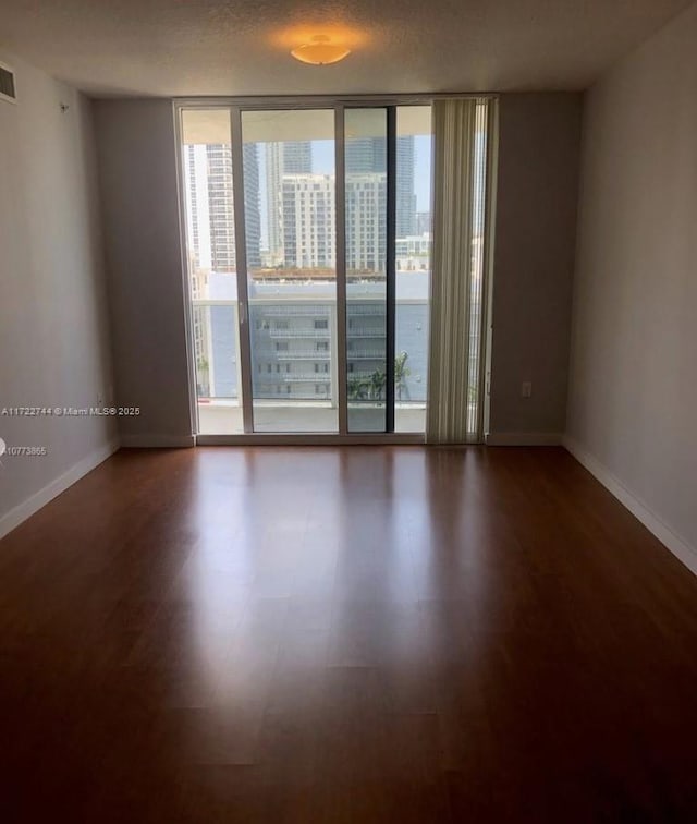 unfurnished room featuring hardwood / wood-style flooring and a wall of windows