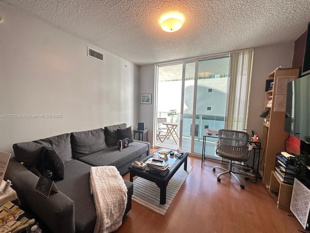 living room with visible vents, a wall of windows, wood finished floors, and a textured ceiling