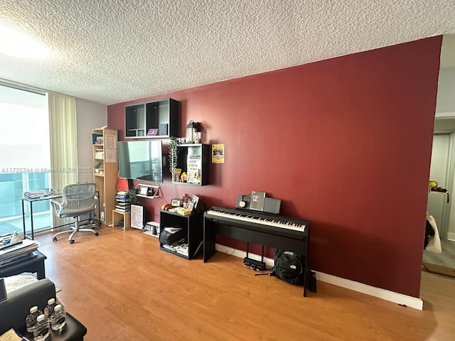 home office with a textured ceiling, wood finished floors, and baseboards