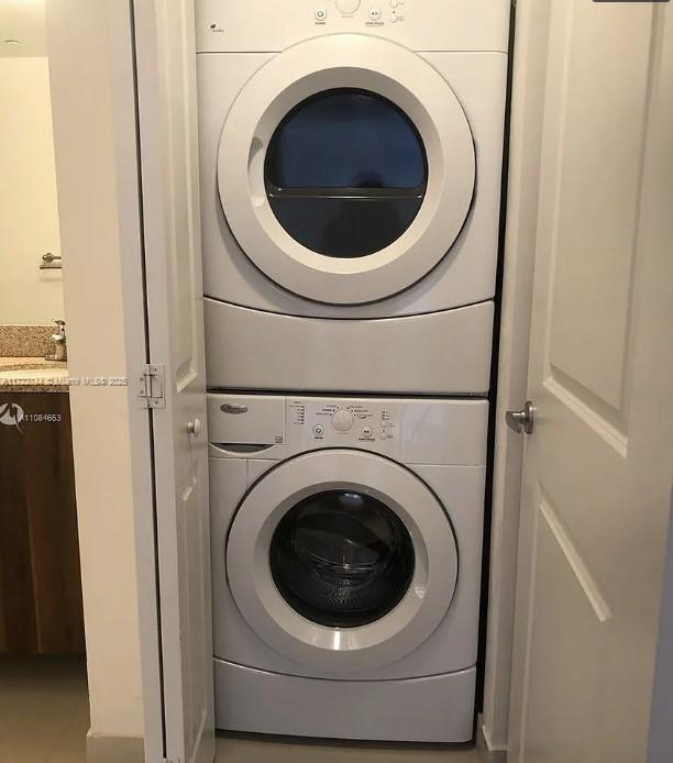 laundry area with laundry area, a sink, and stacked washer and clothes dryer