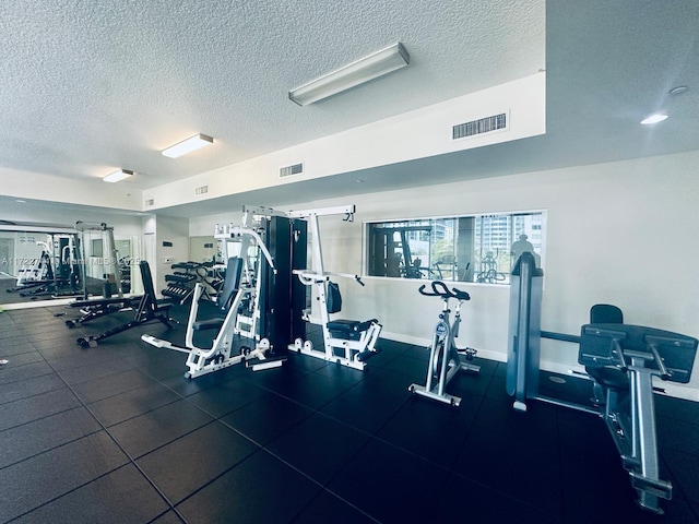 gym with a textured ceiling, visible vents, and baseboards