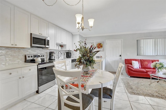 kitchen featuring white cabinets, decorative light fixtures, ornamental molding, and appliances with stainless steel finishes