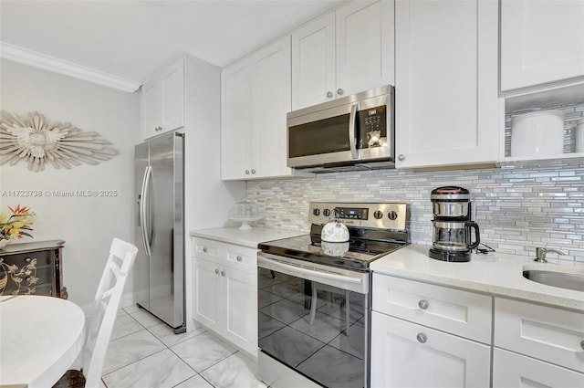 kitchen featuring decorative backsplash, appliances with stainless steel finishes, ornamental molding, sink, and white cabinetry