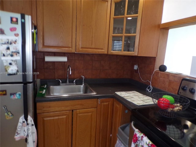 kitchen with backsplash, black electric range oven, sink, and stainless steel refrigerator