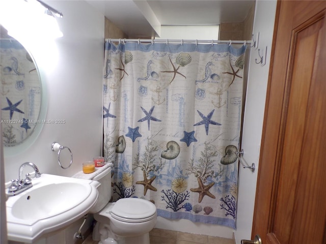 bathroom with a shower with curtain, toilet, sink, and tile patterned flooring