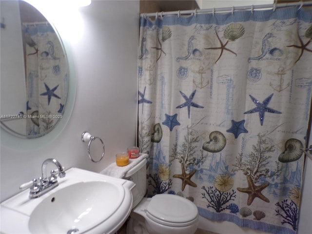 bathroom featuring toilet, curtained shower, and sink