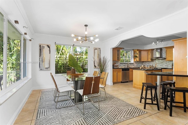 tiled dining area featuring rail lighting, an inviting chandelier, and ornamental molding