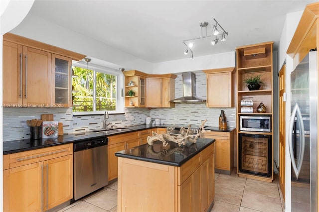 kitchen with sink, a center island, wall chimney range hood, light tile patterned floors, and appliances with stainless steel finishes