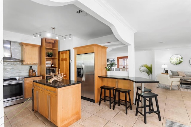 kitchen featuring decorative backsplash, appliances with stainless steel finishes, a kitchen island, and wall chimney exhaust hood