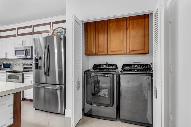 washroom featuring cabinet space, washer and clothes dryer, and light tile patterned floors