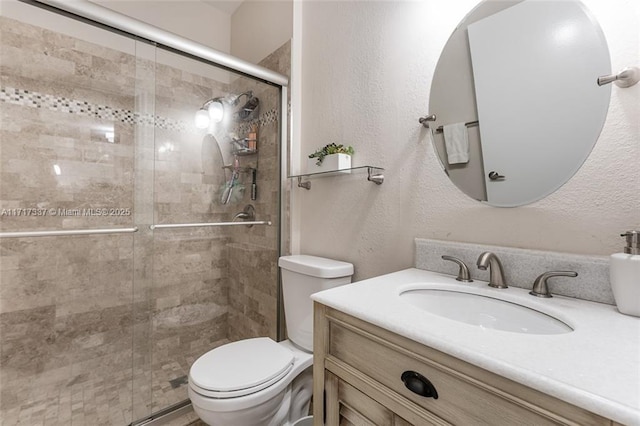 full bath featuring a textured wall, a shower stall, toilet, and vanity