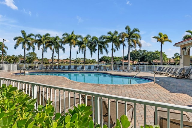 community pool with a patio area and fence