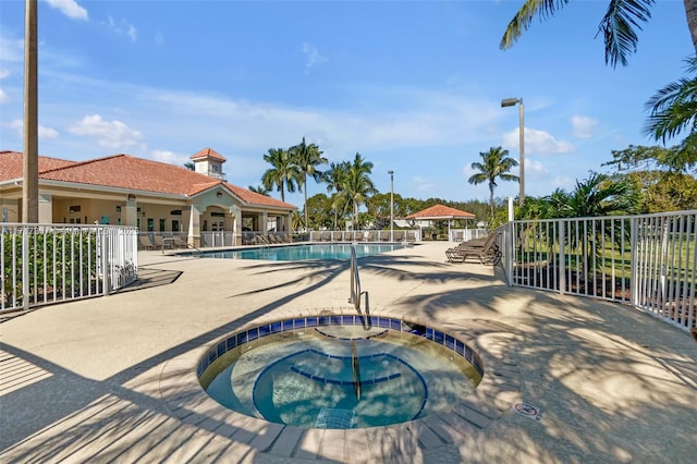 pool featuring a patio area, fence, and a hot tub