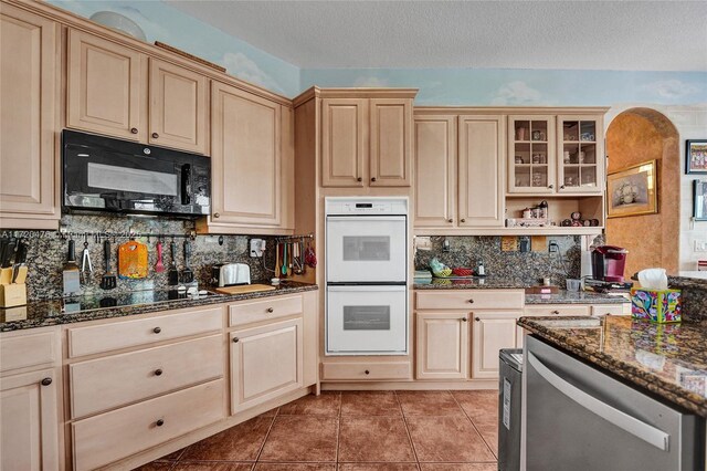 kitchen with backsplash, black appliances, a textured ceiling, and dark stone countertops